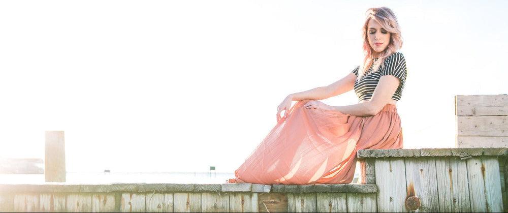 Woman sitting on a wooden dock by a body of water