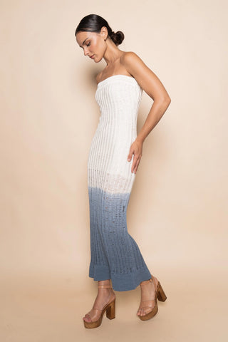 Woman wearing a strapless, white to blue gradient dress against a beige background