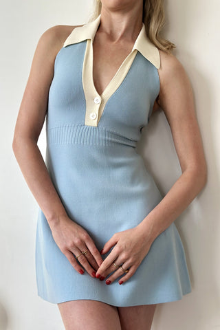 A woman wearing a baby blue knit mini dress with a classic collar and contrasting collar detail, posing against a neutral background.