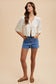 Woman wearing a white blouse and blue shorts on a beige background