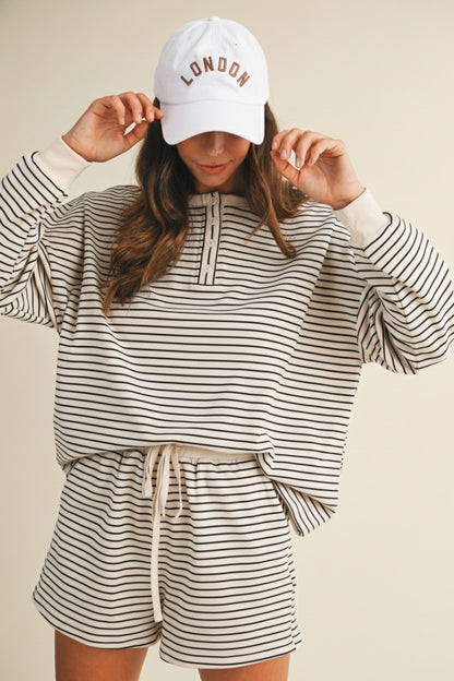 Person wearing a striped outfit and 'London' cap on a beige background