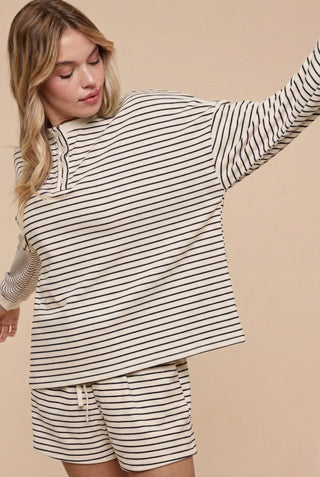 Woman wearing a striped long-sleeve top and shorts on a beige background