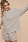 Woman wearing a striped long-sleeve top and shorts on a beige background