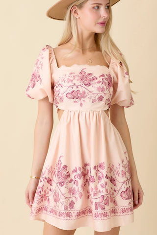 A woman wearing a vintage-inspired pink mini dress with floral patterns and scallop detailing, featuring puff sleeves.