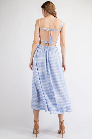 Woman wearing a blue and white checkered dress with an open back on a white background