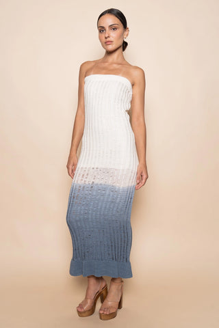 Woman wearing a strapless dress with a white top and blue bottom on a beige background