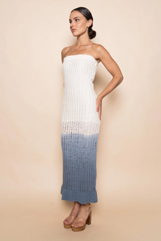 Woman wearing a strapless dress with a white top and blue bottom on a beige background