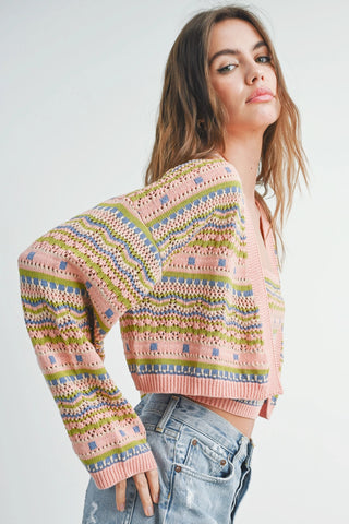 A female model wearing a mauve and multicolor striped pattern cardigan with long sleeves, paired with frayed hem jeans.