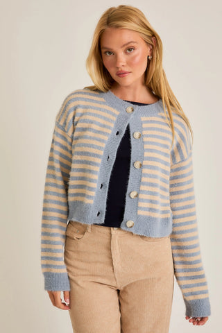 A female model wearing a light blue and cream striped cardigan with a crew neckline, long sleeves, and a button-up front.