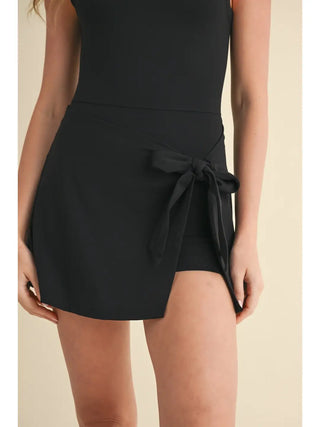 Black dress with a tie waist on a beige background
