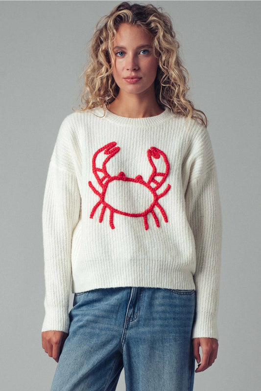 Woman wearing a white sweater with a red crab design on a gray background