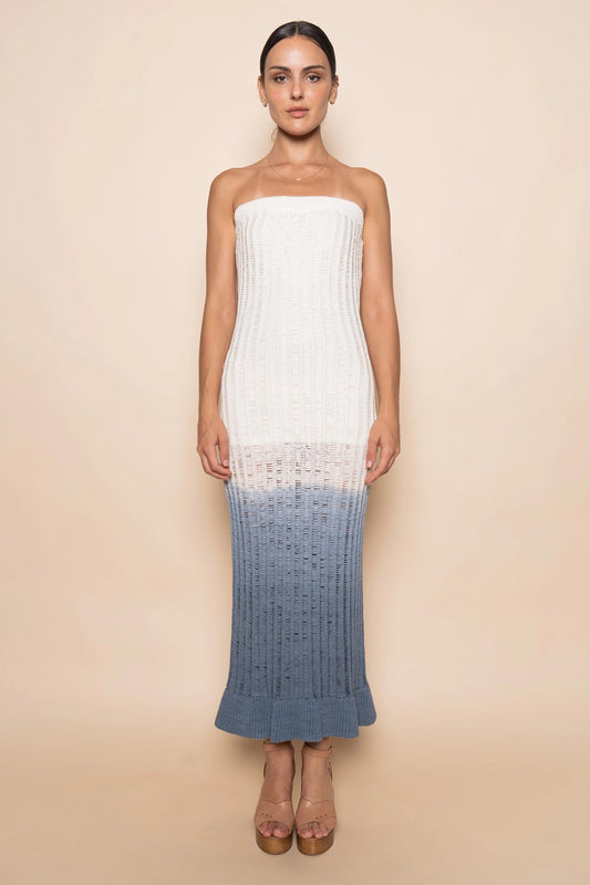 Woman wearing a strapless dress with a white top and blue gradient skirt on a beige background